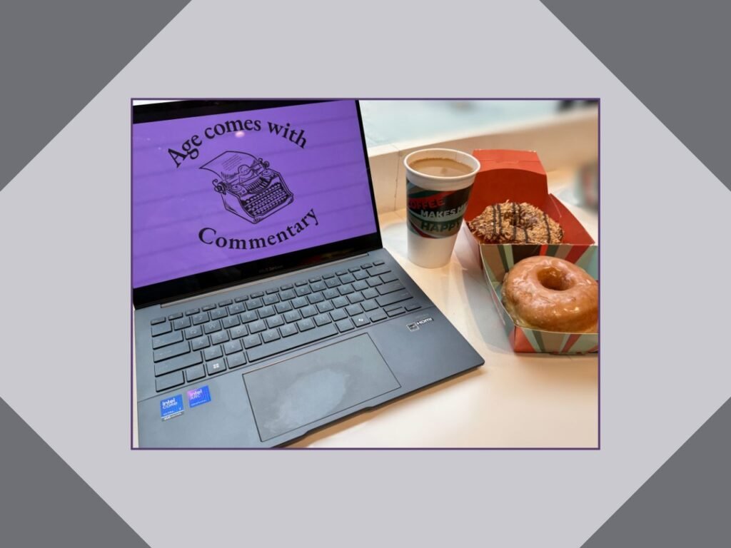 Grey laptop with deep purple background with Age of Commentary Logo on the screen, donuts and coffee.