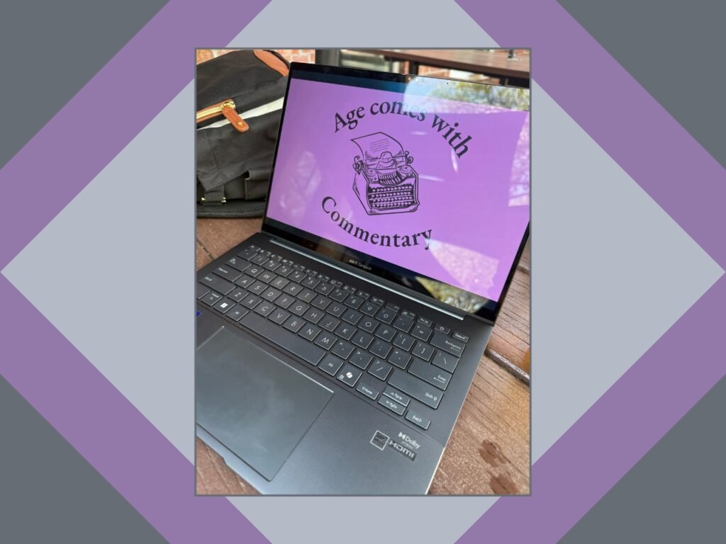 An open laptop on an outdoor patio table displaying the Age comes with Commentary logo.